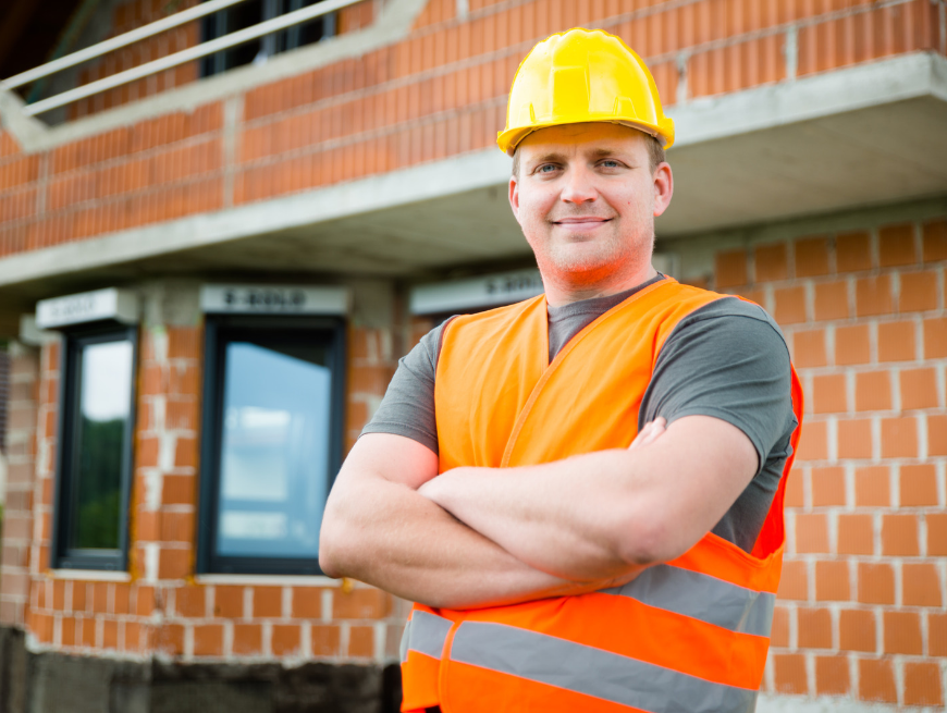 Aannemer met bouwhelm en oranje hesje voor een nieuwbouwwoning